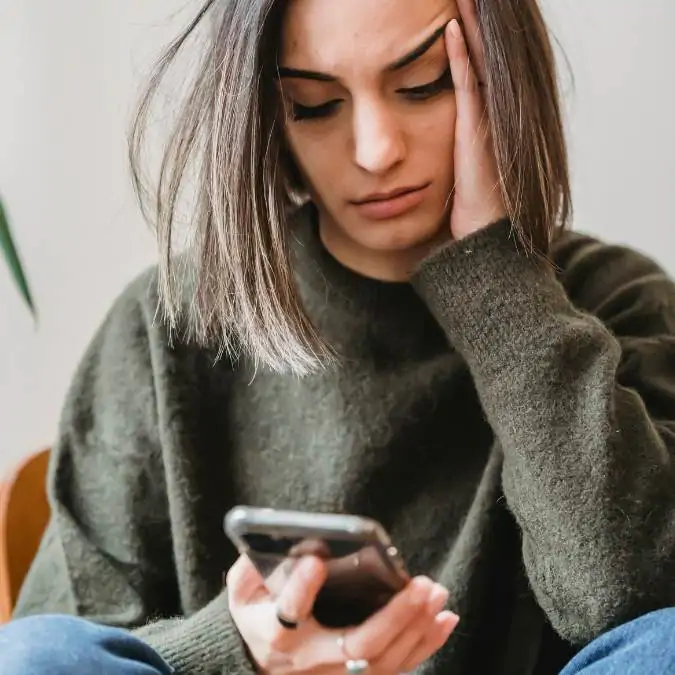 mulher usando o celular - com rosto de preocupação